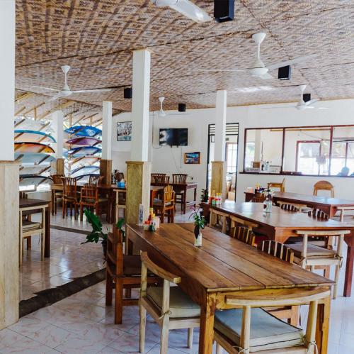 comedor con mesas y sillas de madera en Anugerah Surf & Dive, en Nembrala