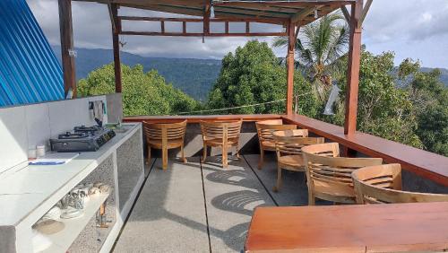 a balcony with chairs and tables and a view at Puri Pilihani Hostel in Munduk