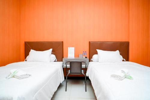 dos camas sentadas una al lado de la otra en una habitación en Mess Rejeki Redpartner en Sampit
