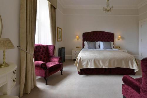 a bedroom with a large bed and two chairs at Wellwood Manor in Pitlochry