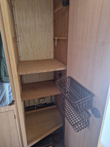 un placard avec des étagères en bois et deux paniers dans l'établissement Camping La Foret du Morvan Caravan Joost, à Larochemillay
