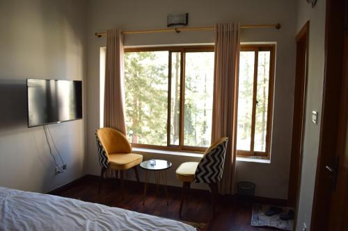 a bedroom with a bed and two chairs and a window at Royal House in Nathia Gali