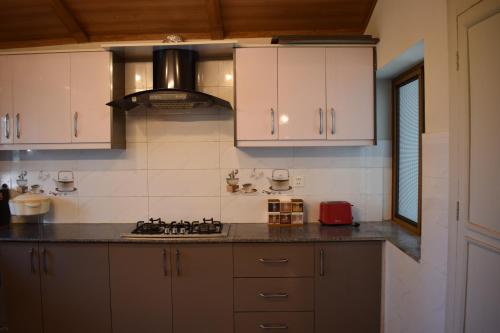 a kitchen with white cabinets and a stove top oven at Serenity House in Nathia Gali
