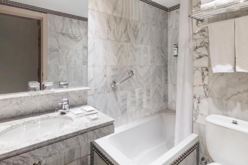 a white bathroom with a tub and a sink at Catalonia Hispalis in Seville