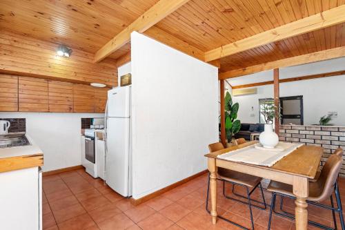 a kitchen with a table and a white refrigerator at 14 Cottesloe - steps from beach - sleeps 2 in Perth