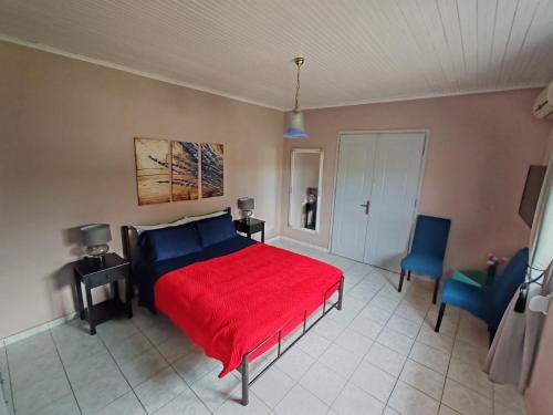 a bedroom with a red bed and two blue chairs at ELVAJO Apartment in Zakharo