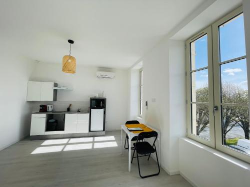 une cuisine blanche avec une table et une fenêtre dans l'établissement Le Lussaut, à Saint-Jean-dʼAngély