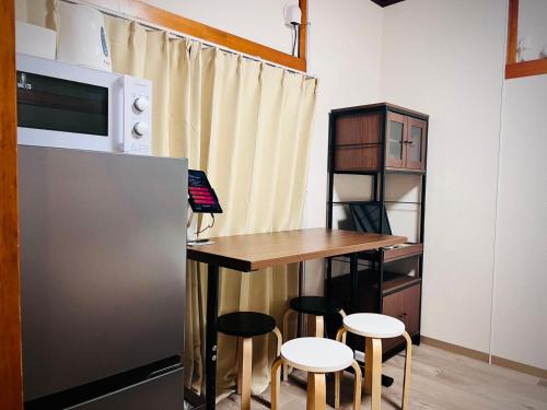 a kitchen with a table and stools next to a refrigerator at 桜Home in Tokyo