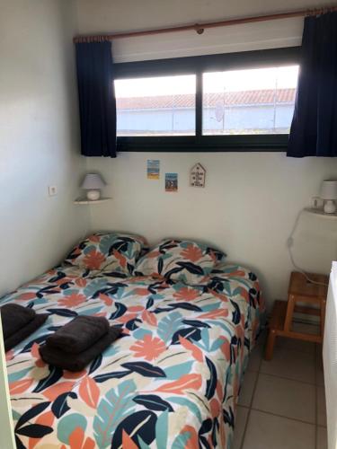 1 dormitorio con cama con edredón y ventana en Appartement bord de mer, en La Tranche-sur-Mer