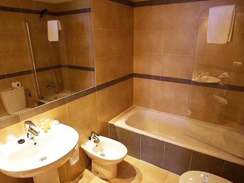 La salle de bains est pourvue d'un lavabo, de toilettes et d'une baignoire. dans l'établissement Apartamentos Esmeralda Suites Unitursa, à Calp