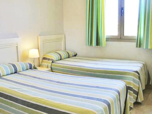 2 camas en una habitación con cortinas verdes y azules en Apartamentos Esmeralda Suites Unitursa, en Calpe