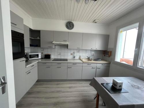 kuchnia z białymi szafkami, stołem i oknem w obiekcie Maison idéalement située pour les vacances w mieście Notre-Dame-de-Monts