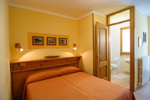 a bedroom with an orange bed and a bathroom at Albergo Boschetto Ristorante Pizzeria in Druogno