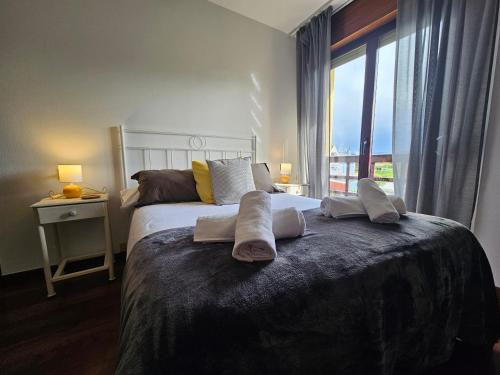 1 dormitorio con cama con almohadas y ventana en Apartamento Ría Navia El Espín 31A01, en Navia