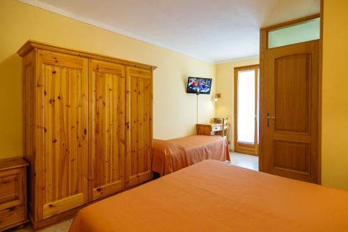 a bedroom with two beds and a tv in it at Albergo Boschetto Ristorante Pizzeria in Druogno