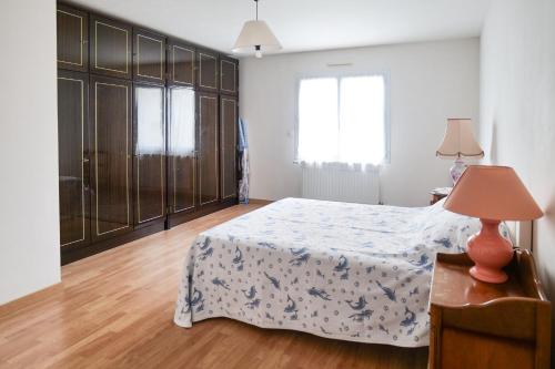 ein Schlafzimmer mit einem Bett und einem Tisch mit einer Lampe in der Unterkunft Spacieuse maison avec extérieur quartier Arago Les Sables 7 personnes in Les Sables-dʼOlonne