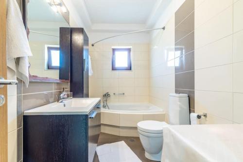 a bathroom with a sink and a toilet and a tub at Vacation House close to the Beach in Elia