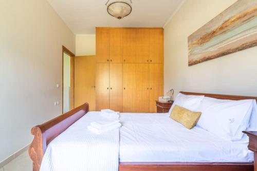 a bedroom with a white bed with a wooden headboard at Vacation House close to the Beach in Elia