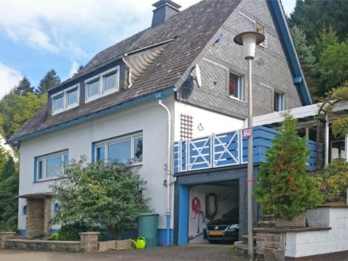 a white house with a blue roof at Spacious apartment in Rattlar with private terrace in Willingen