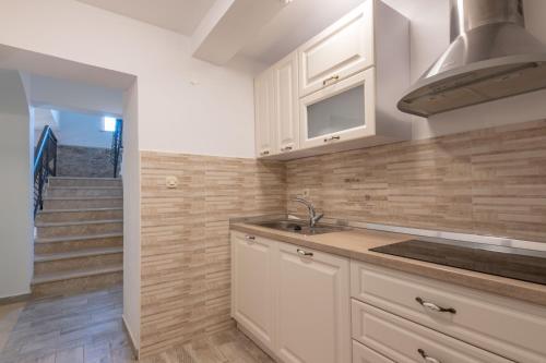 eine Küche mit weißen Schränken, einem Waschbecken und einer Treppe in der Unterkunft Villa Tupljak, luxury and comfort in a hidden summer hideout in Gromnik