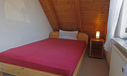 a small bedroom with a bed with a red blanket at Kleines Nest in Westerrönfeld