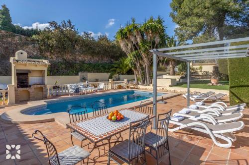 a patio with a table and chairs next to a pool at Villa Baladrar by Abahana Villas in Benissa
