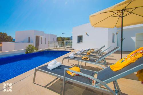 eine Gruppe von Stühlen und einem Sonnenschirm neben einem Pool in der Unterkunft Villa Baydal by Abahana Villas in Benissa