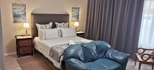 a bedroom with a large bed and a blue leather couch at Mila's at Panorama in Cape Town