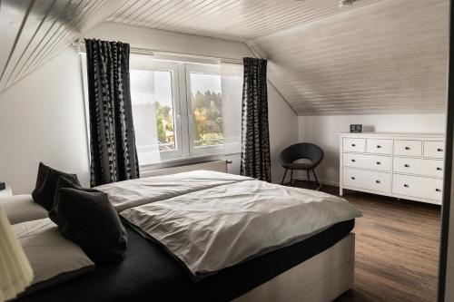 um quarto com uma cama, uma janela e uma cadeira em Ferienwohnung Fichtelblick em Schönwald