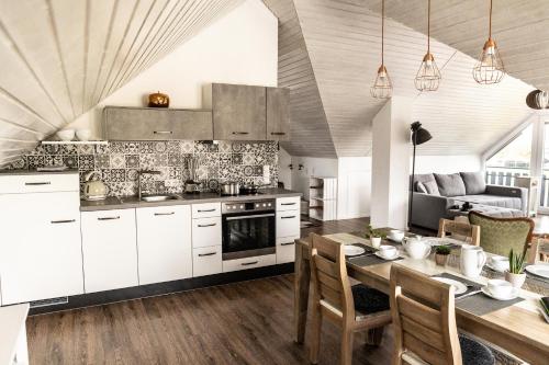 a kitchen with white cabinets and a wooden table at Ferienwohnung Fichtelblick in Schönwald