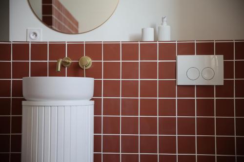 a bathroom with a toilet and a mirror and red tiles at Lomalia in Parmain