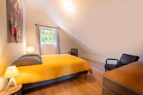 a bedroom with a yellow bed and two chairs at Gite ty laouen in Sarzeau