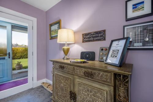 a room with a table with a lamp and a window at Orcadia Sutherland Road Dornoch IV25 3SX in Dornoch