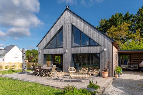 a barn style house with glass windows and a patio at Gite ty laouen in Sarzeau
