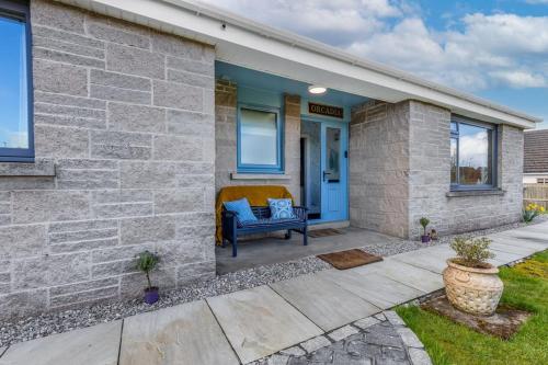 a brick house with a blue door and a bench at Orcadia Sutherland Road Dornoch IV25 3SX in Dornoch