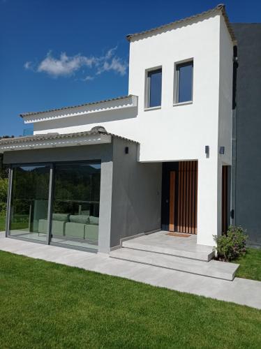 a white house with glass doors and a lawn at La Casa Del Rio in Kymi