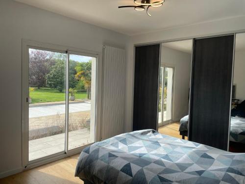 Schlafzimmer mit einem Bett und Glasschiebetüren in der Unterkunft Villa luxueuse in Allonnes