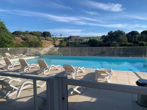 une terrasse avec des chaises et une piscine dans l'établissement Jolie appartement dans résidence avec piscine, à Carnoux-en-Provence
