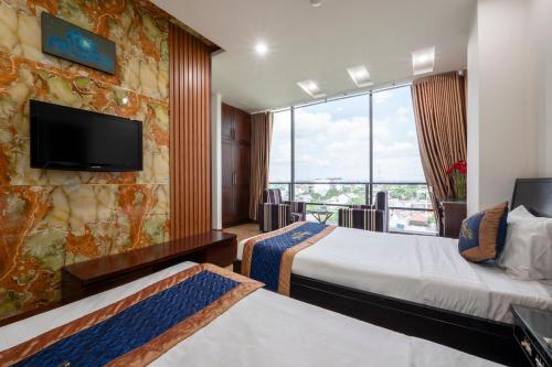 um quarto de hotel com duas camas e uma televisão de ecrã plano em Thien Phu Logia Hotel em Ho Chi Minh