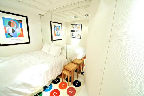 Un pequeño dormitorio con 2 camas y un taburete en Notre Dame In Full Colors en París
