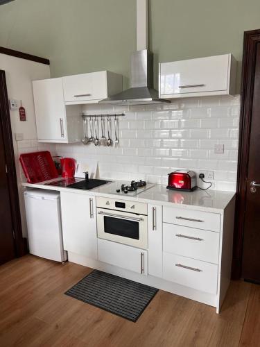 une cuisine avec des armoires blanches et un appareil rouge dans l'établissement STUDIO APARTMENT PAISLEY ROAD WEST, à Glasgow