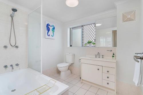 a white bathroom with a tub and a toilet and a sink at Relaxation Awaits at Runaway Cove in Gold Coast
