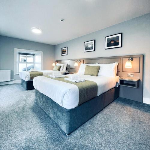 a hotel room with two beds and two windows at The Bridge Tavern in Wicklow