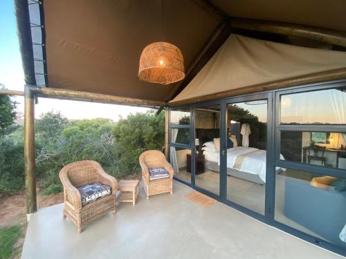 a room with a bed and two wicker chairs at Charihandra Game Lodge in Addo