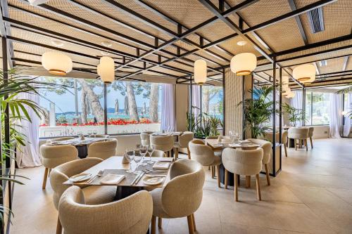 a restaurant with tables and chairs and large windows at Hotel Illa d'Or & Club Apts 4* Sup in Port de Pollensa