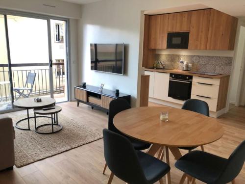 un salon avec une table et des chaises et une cuisine dans l'établissement Cannes Appartement neuf tout confort, au Cannet