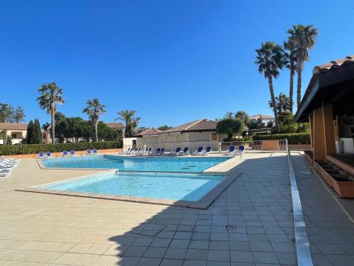 - une piscine bordée de chaises et de palmiers dans l'établissement Résidence marine de bravone Accès plage, Piscine, à Linguizzetta