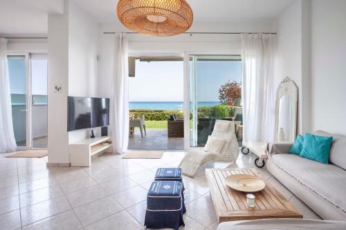 a living room with a couch and a tv and the ocean at Seapalm House in Hanioti