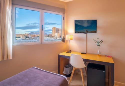a bedroom with a desk and a bed and a window at La City Estación in Alicante
