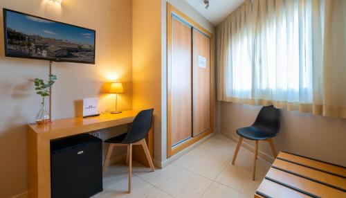 a room with a desk and two chairs and a window at La City Estación in Alicante